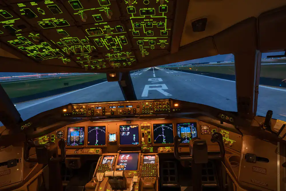 Pilot's perspective from inside a commercial airliner simulator cockpit with glowing instruments